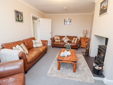 A living room with brown leather sofas a wooden coffee table and a fireplace at Bryn Seion in Y Felinheli