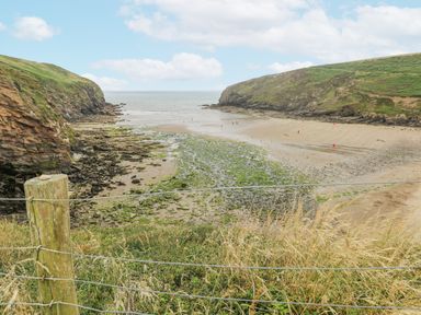 A coastal cove with a sandy beach and rocky cliffs at Hillbrook House in Nolton Haven