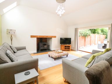 A living room with two grey sofas a fireplace a television and a sliding door to an outdoor patio at Oak Tree Lodge in Crostwick near Norwich