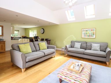 A living room with two gray sofas and an ottoman with a tea set at Oak Tree Lodge in Crostwick near Norwich