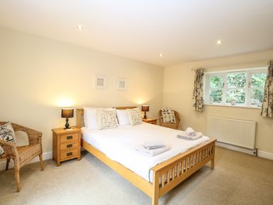A bedroom with a wooden double bed bedside tables lamps wicker chairs and a window at Oak Tree Lodge Crostwick near Norwich