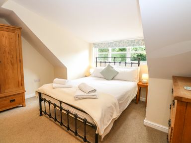 A bedroom with a bed with white linens and towels wooden furniture and a window at Oak Tree Lodge in Crostwick near Norwich