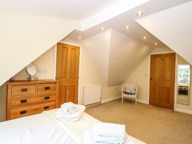 A bedroom with a wooden dresser a white chair towels on the bed and two wooden doors at Oak Tree Lodge Crostwick near Norwich