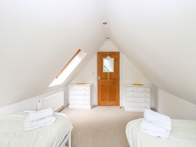 A bedroom with two single beds white dressers and a wooden door at Oak Tree Lodge Crostwick near Norwich