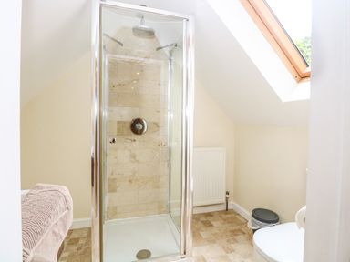 A bathroom with a glass shower cubicle a toilet a trash bin and a window at Oak Tree Lodge Crostwick near Norwich