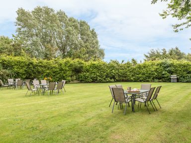 An outdoor garden area with multiple tables and chairs on a grass lawn at Dorothy's Cottage in Alnmouth