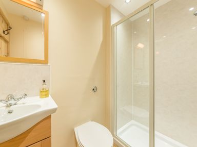 A bathroom with a sink and mirror a toilet and a shower enclosure at Dorothy's Cottage in Alnmouth