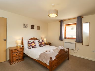 A bedroom with a wooden double bed and two bedside tables at Brindle Cottage in Royal Wootton Bassett