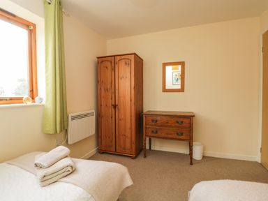 A bedroom with a wooden wardrobe a wooden dresser and a bed with towels on it at Brindle Cottage in Royal Wootton Bassett