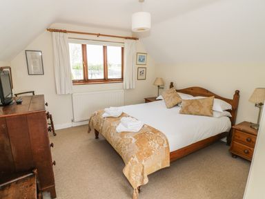 A bedroom with a double bed two bedside tables a chest of drawers and a window at Highcroft in Stratford-Upon-Avon