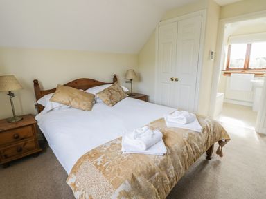 A bedroom with a double bed bedside tables lamps and an adjoining bathroom at Highcroft in Stratford-Upon-Avon