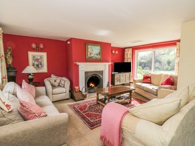 A living room with sofas pillows a fireplace coffee table and large window at Highcroft in Stratford-Upon-Avon