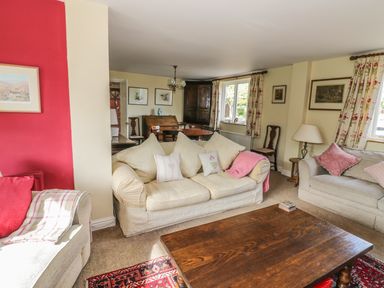 A living room with cream sofas and wooden coffee table at Highcroft in Stratford-Upon-Avon