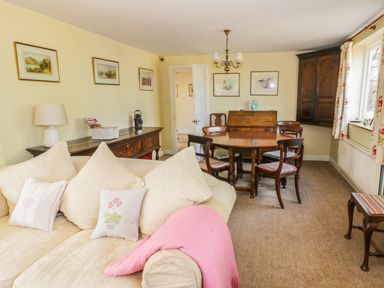 A living room with a beige sofa and wooden dining table with chairs at Highcroft in Stratford-Upon-Avon