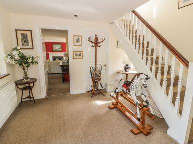 A hallway with a rocking horse near stairs and a wooden coat rack at Highcroft  Stratford-Upon-Avon