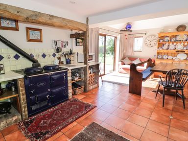 A kitchen and dining area with a blue stove wooden dining table and a sofa near sliding glass doors at Highcroft in Stratford-Upon-Avon
