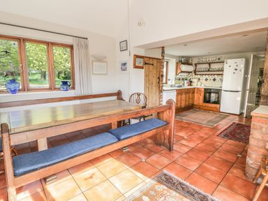A kitchen and dining area with wooden furniture and tiled floors at Highcroft in Stratford-Upon-Avon