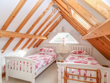 A bedroom with two single beds with floral bedding under a wooden beamed ceiling at Stable Cottage in Necton near Swaffham