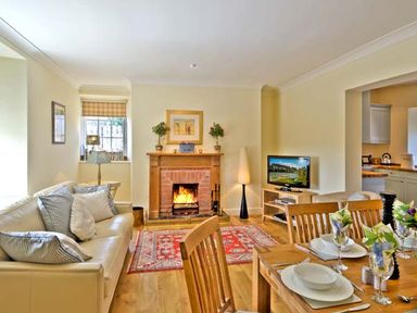 A living room with a fireplace a sofa and a dining table set at The Old Farmhouse in Lowick