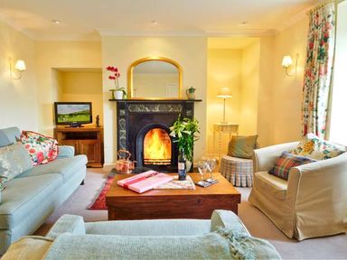 A living room with a fireplace and seating area at The Old Farmhouse in Lowick