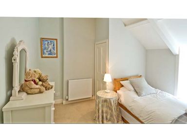 A small bedroom with a single bed side table with lamp a dresser with teddy bears and a framed picture on the wall at The Old Farmhouse in Lowick