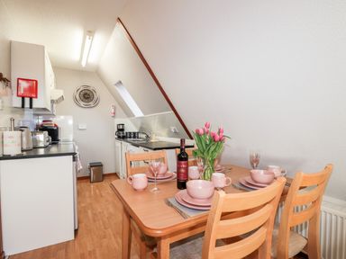 A kitchen and dining area with wooden table set for four and kitchen appliances at Larchfield Chalet 2 in Heights of Achterneed near Strathpeffer
