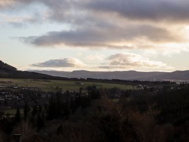 A landscape with fields trees scattered houses and hills under a cloudy sky at Larchfield Chalet 2 Heights of Achterneed near Strathpeffer