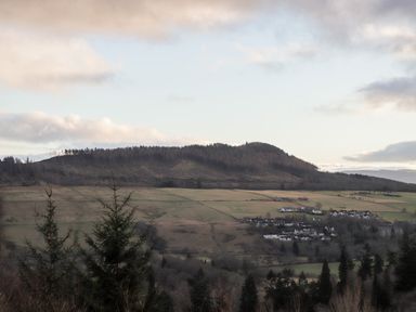 A rural landscape with trees hills and a small village in the distance at Larchfield Chalet 2 Heights of Achterneed near Strathpeffer