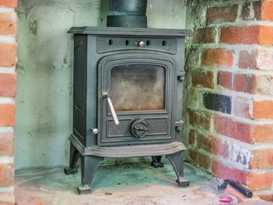 A black wood burning stove set in a brick fireplace at Endymion in Linwood near Ringwood New Forest