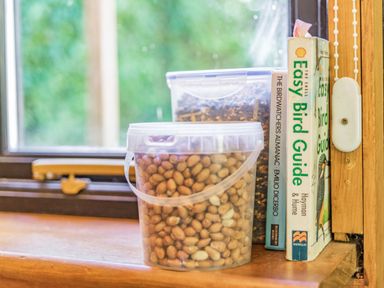 A window ledge with plastic containers of bird food and bird guide books at Endymion in Linwood near Ringwood New Forest