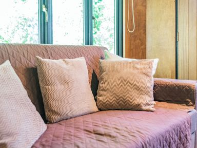 A sofa with patterned cushions in front of a window at Endymion in Linwood near Ringwood New Forest
