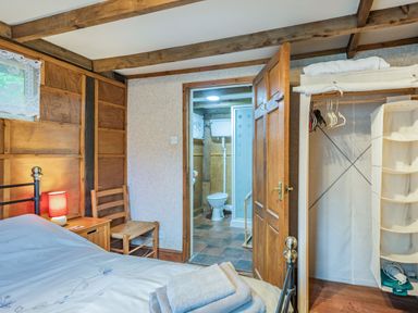 A bedroom with a bed chair nightstand and open door leading to a bathroom at Endymion Linwood near Ringwood New Forest