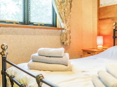 A bedroom with a metal bed frame and folded towels on the bed at Endymion in Linwood near Ringwood New Forest