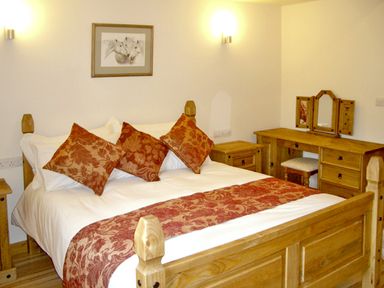 A bedroom with a wooden bed and furniture including a dressing table at Happy Union Stables in Abbeycwmhir near Rhayader