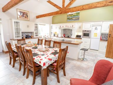 A kitchen and dining area with wooden furniture and exposed beams at Prague House in Lettermore County Galway