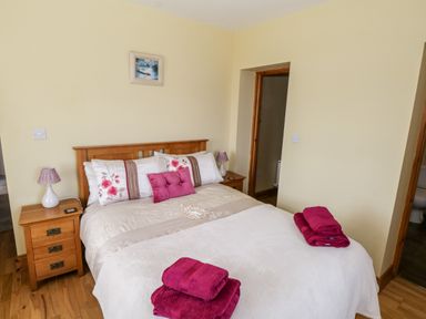 A bedroom with a wooden bed and bedside tables with lamps at Prague House in Lettermore County Galway