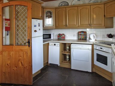A kitchen with wooden cabinets white appliances a microwave a kettle and spice rack at Delia's Cottage in Ballinrobe County Mayo