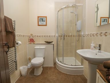 A bathroom with a toilet shower sink towel rack and framed picture at Woodside Barn in Pennington near Ulverston