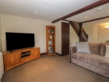 A living room with a television and a bookshelf at Woodside Barn Pennington near Ulverston