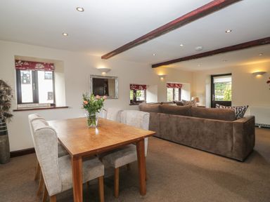 A living room with a dining table and sofa at Woodside Barn Pennington near Ulverston