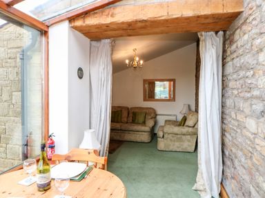 A living room with two beige sofas a wooden dining table and a glass window at The Stable in Milton near Brampton