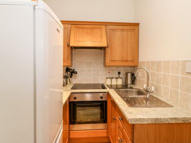 A kitchen with wooden cabinets a stainless steel oven a sink a kettle and a refrigerator at The Stable Milton near Brampton
