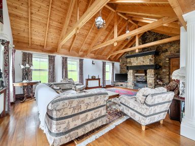 A living room with sofas, a coffee table, and a fireplace at Chapel Green in Polgooth