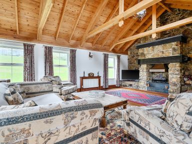 A living room with a sofa, coffee table, and fireplace at Chapel Green in Polgooth