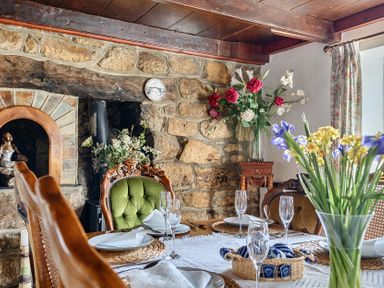A dining room with a table set for meals at Chapel Green in Polgooth