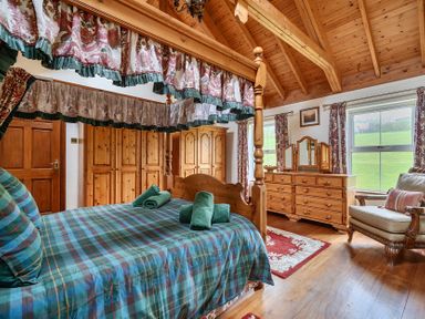 A bedroom with a four-poster bed and wooden furniture at Chapel Green in Polgooth
