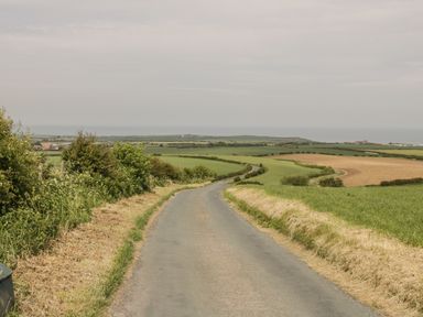 A country road surrounded by fields and bushes with a distant view of the sea at Barn Cottage in High Normanby near Robin Hood's Bay