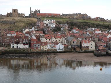 A coastal town with red roofed houses along the water and historic stone buildings on a hill at Barn Cottage in High Normanby near Robin Hood's Bay