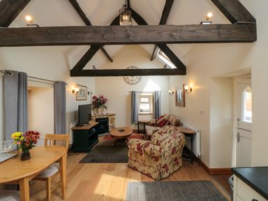A living room with wooden beams a dining table armchairs and a fireplace at Barn Cottage High Normanby near Robin Hoods Bay