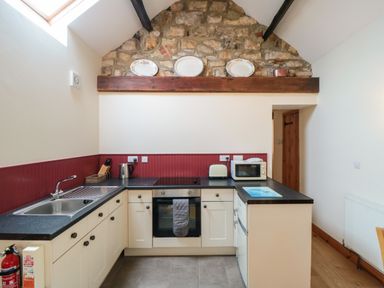 A kitchen with a sink stove microwave toaster and stone wall at Barn Cottage in High Normanby near Robin Hood's Bay